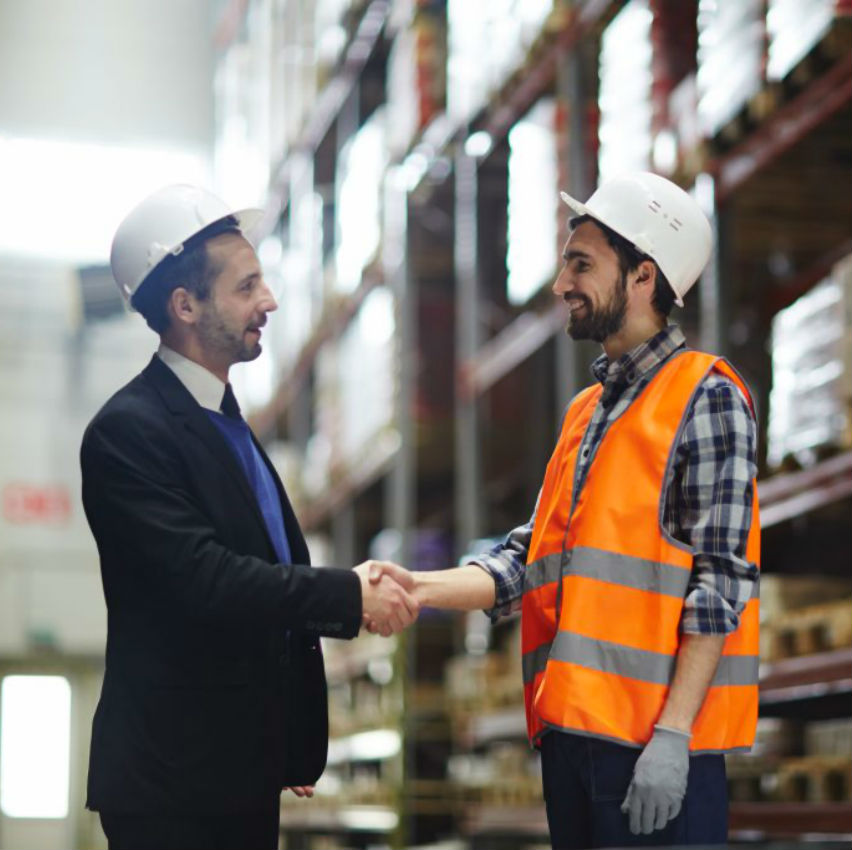 Deux collègues se serrent la main dans un entrepôt de marchandises